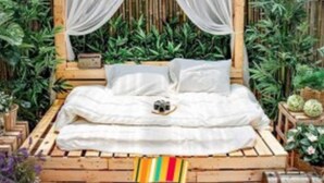 A bed with a canopy, surrounded by plants, in a room with bamboo walls. - Quynh Huong Hotel (Ho Chi Minh City)