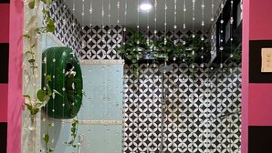 A bathroom with a white bathtub, a green planter, and a patterned wall. - Quynh Huong Hotel (Ho Chi Minh City)