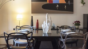 A dining area with a table set for four, chairs, a lamp, a decorative vase, and a wall art piece.