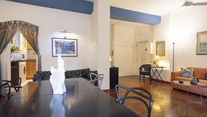 A modern living room with a dining area, featuring a large wooden table, a sofa, and a coffee table.