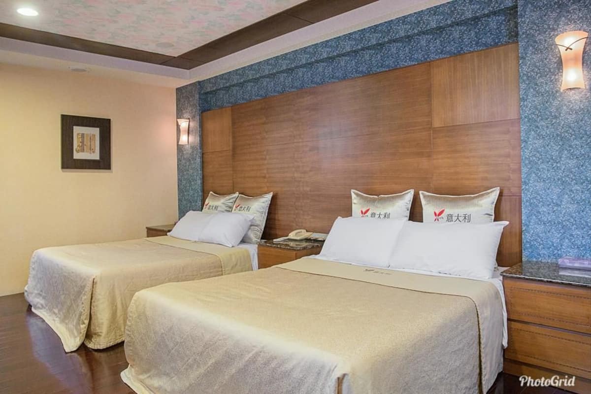 A hotel room with two beds, wooden headboards, and a framed picture on the wall.