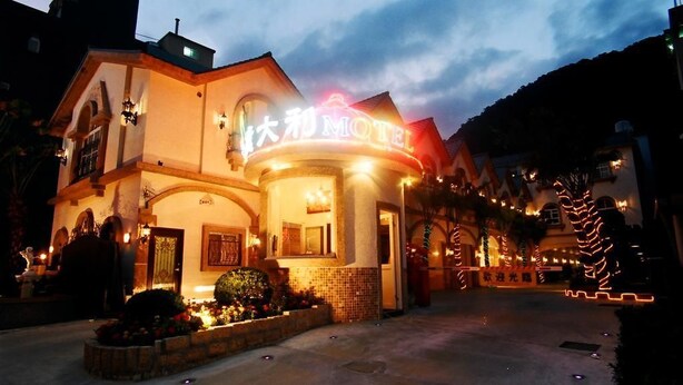 Un motel con un letrero llamativo, ventanas en arco y una entrada bien iluminada.