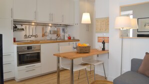 A modern kitchen with white cabinets, a wooden countertop, and a dining area with a table and chairs. - RH FACTORY 15, Lisbon Apartment (Lisboa)