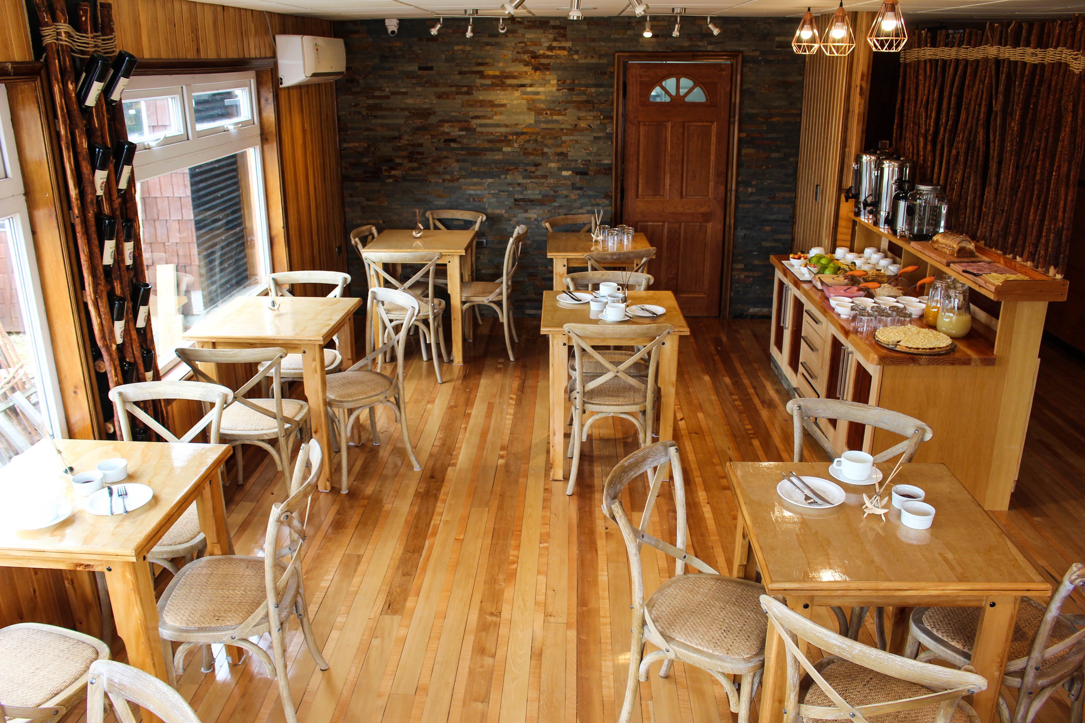 Un restaurante acogedor con mesas y sillas de madera, una pared de piedra y una barra de desayuno con diferentes platos.