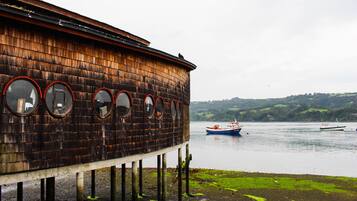 A wooden building with circular windows and a view of boats on the water.