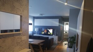 Ein modernes Wohnzimmer mit Fernseher, Sofa und Essbereich.