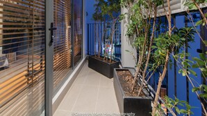 A modern interior with a glass door, a tiled floor, and a potted plant. - Mojzo Inn Boutique (Nha Trang)