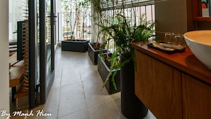 A modern bathroom with a large window, a wooden vanity, and potted plants. - Mojzo Inn Boutique (Nha Trang)