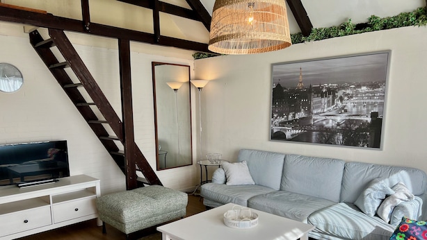 Ein modernes Wohnzimmer mit einer Couch, einem Fernseher, einem weißen Couchtisch und einem großen Spiegel.