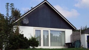 Ein Haus mit dunklem Dach, weißer Fassade und einer großen Glasschiebetür.