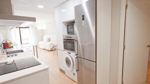 Una cocina moderna con horno empotrado, microondas y lavadora.
