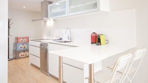 Una cocina moderna con armarios blancos, lavavajillas de acero inoxidable y una pequeña isla con sillas.