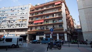 Un edificio de varios pisos con balcones, un letrero que dice 'Tropical House' y una señal de tráfico que indica un giro a la derecha.