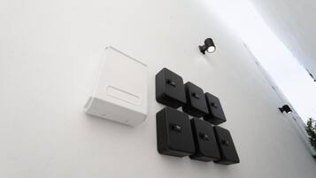 Pared blanca con un portero automático blanco y cuatro porteros automáticos negros montados en ella.