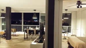 Uma varanda ampla com mesa e cadeiras de jantar, um sofá e uma televisão.