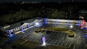Un hôtel à plusieurs étages, doté d’un parking et d’une enseigne indiquant qu’il dispose de 6 chambres.