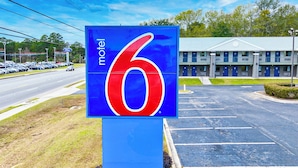 Une enseigne de motel avec le chiffre 6, un parking et le bâtiment du motel en arrière-plan.
