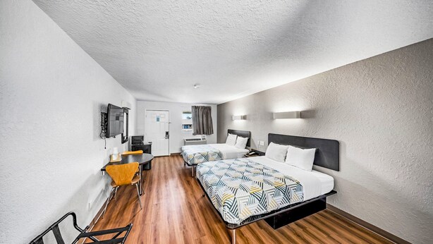 Une chambre d’hôtel avec deux lits, un bureau et une chaise.