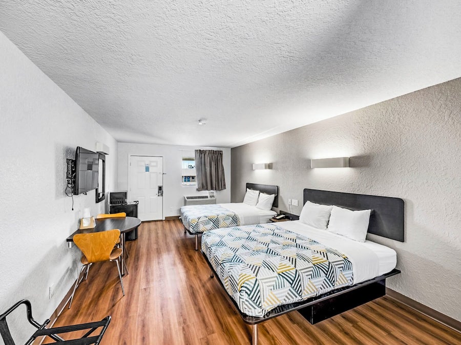 Een hotelkamer met twee bedden, een bureau en een stoel.