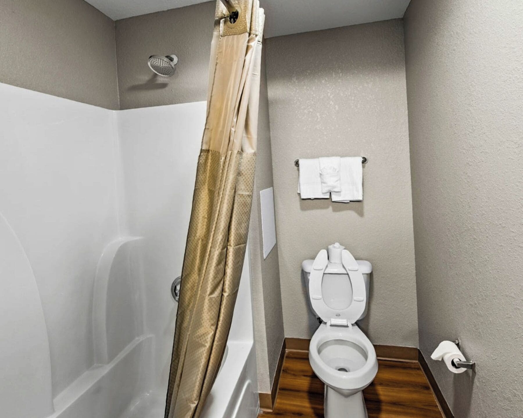A bathroom with a shower, toilet, and towel rack.
