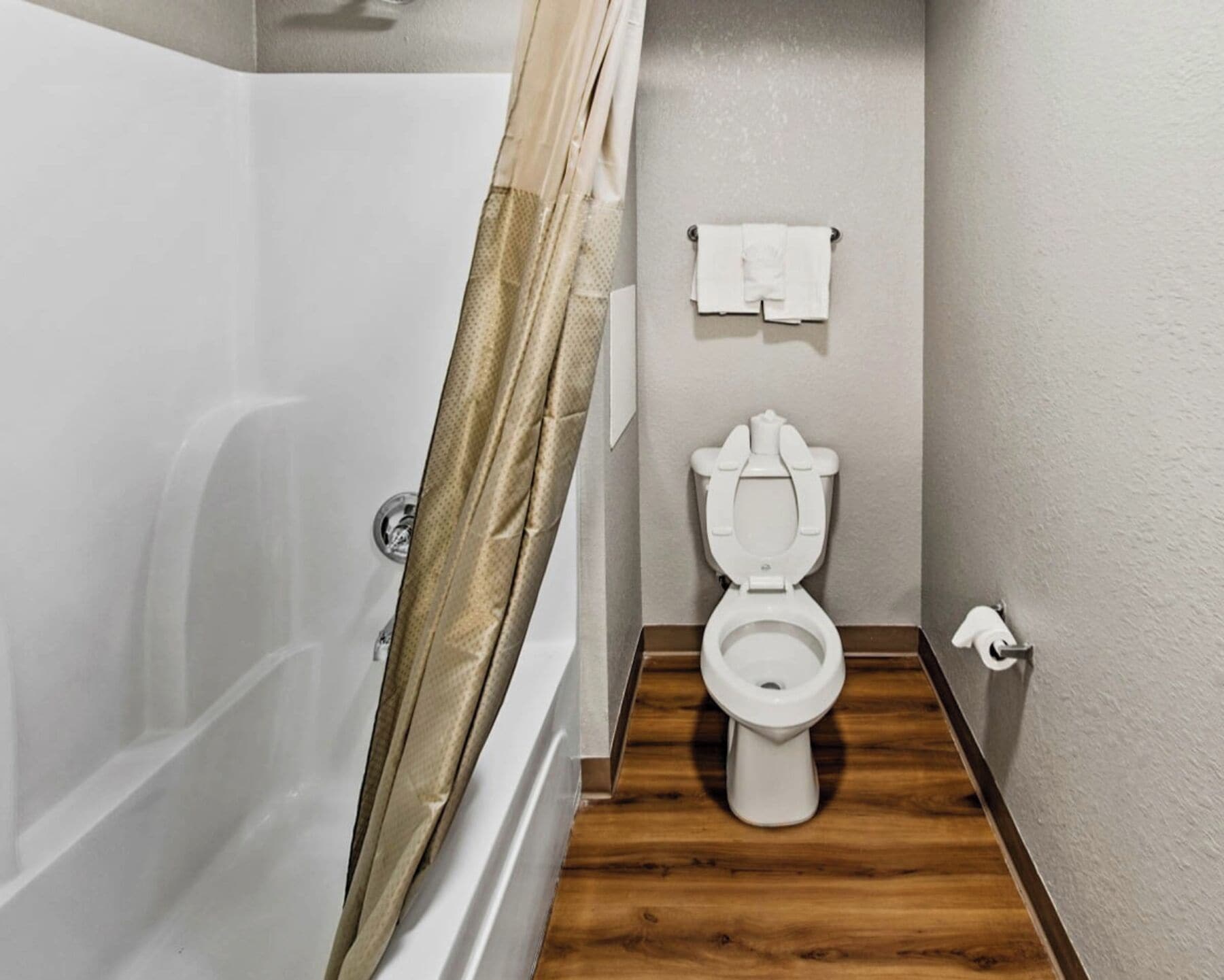 Une salle de bain équipée d’un rideau de douche, de toilettes et d’un porte-serviettes.