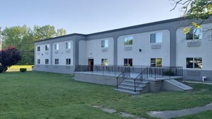 Un edificio moderno con techo plano, varias ventanas y una pequeña escalera exterior que conduce a un área cubierta.
