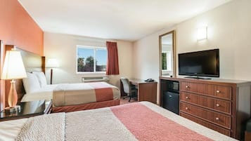 A hotel room with two beds, a desk, a television, and a dresser.