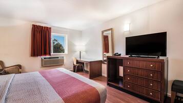 A hotel room with a bed, desk, television, and a chair.