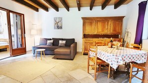 Ein Wohnzimmer mit einer Couch, einem Esstisch mit Stühlen und einer Küchenzeile mit Holdekor.