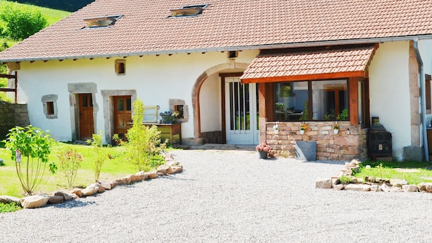 Ein traditionelles Haus mit Ziegeldach, Steineingang und Schotterweg.