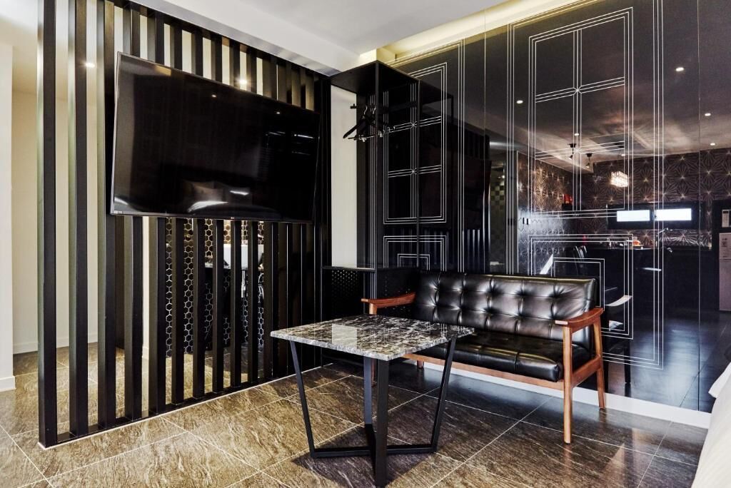 Una sala de estar moderna con un sofá de cuero, una mesa de centro de mármol y un televisor montado en la pared con un panel decorativo.