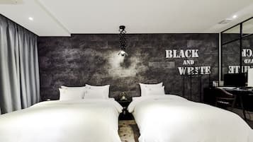 A modern bedroom with two beds, a dark textured wall, and a mirror with a black and white sign.