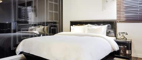 Un dormitorio con una cama grande, un armario y una mesita de noche con lámpara.