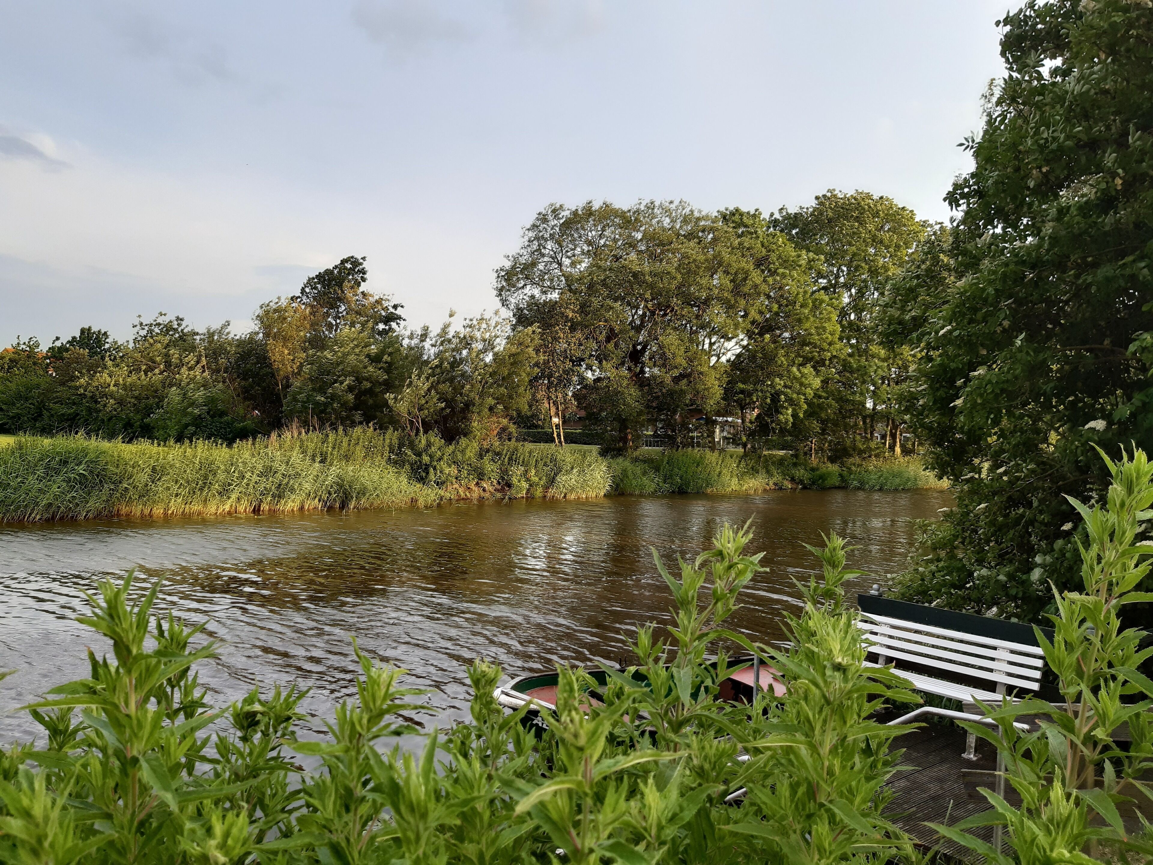 A riverside park with a bench and a boat.