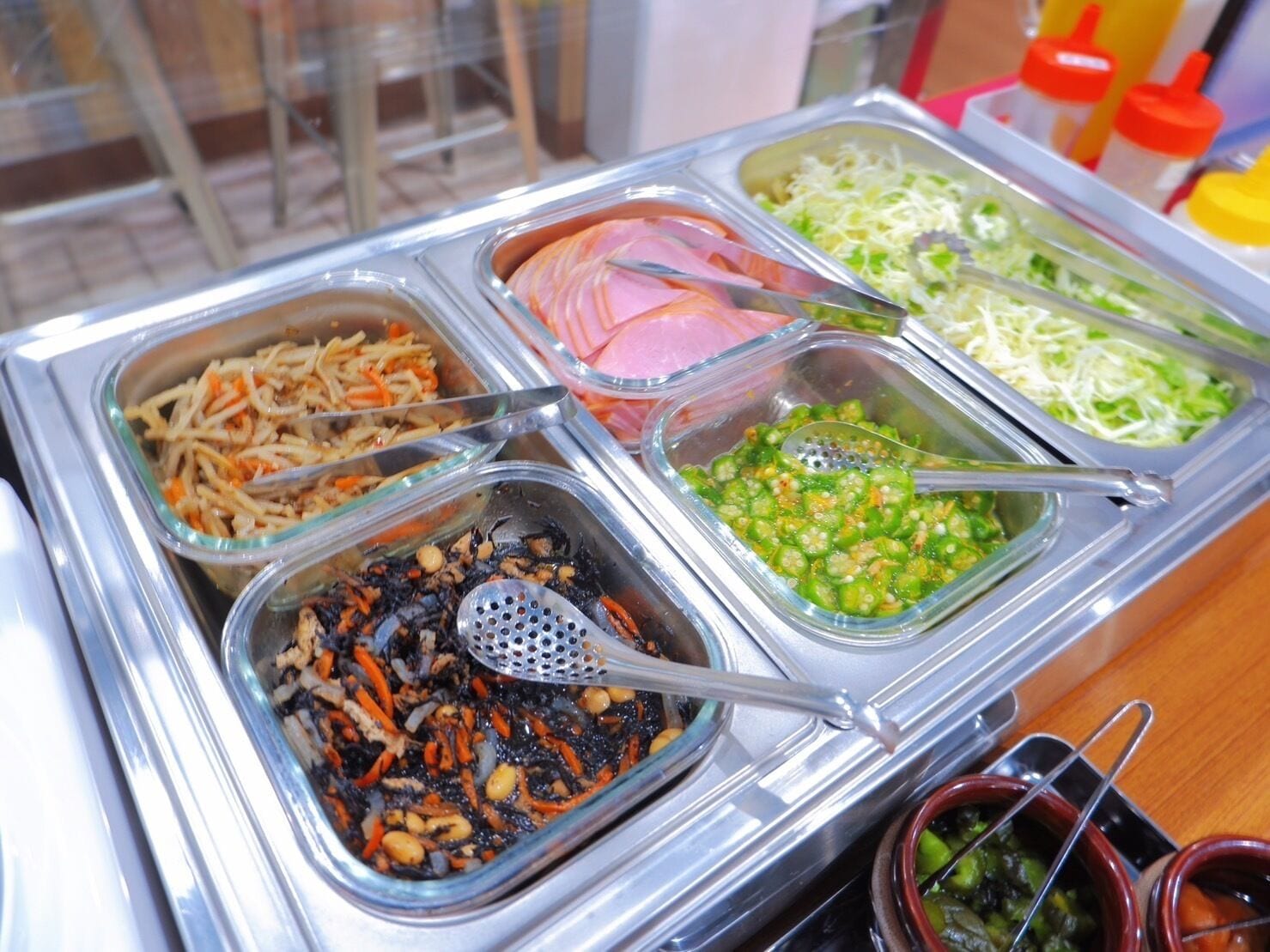 Buffet com diversas opções de comida, incluindo macarrão, carne fatiada e vegetais.