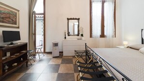 A hotel room with a bed, a desk with a computer, a chair, a dresser, a mirror, and a window with curtains. - Ca Baglioni (Venice)