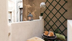 A small balcony with a cushioned stool, a table with a cup and saucer, a lantern, and a potted plant. - Ca Baglioni (Venice)