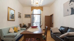 A living room with a wooden dining table, two sofas, a chandelier, and artwork on the walls. - Ca Baglioni (Venice)
