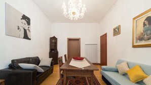A living room with a wooden dining table, a black leather sofa, a light blue sofa, and a patterned rug. - Ca Baglioni (Venice)