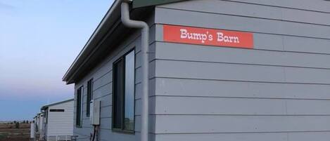 A small, single-story building with a sign reading "Bump's Barn." It has a simple, functional design with a flat roof and a small window.