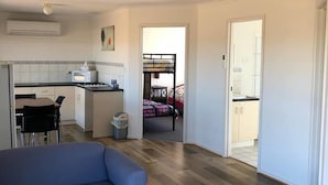 En kompakt bolig med tekøkken, spiseplads og et soveværelse med køjeseng.