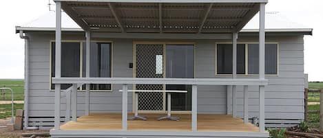 A two-story house with a wooden deck, a covered porch, and a fenced yard.