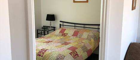 A bedroom with a bed, a nightstand, a lamp, and a framed picture on the wall.