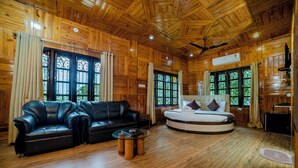 Un intérieur en bois avec un canapé en cuir noir, un lit rond et un ventilateur de plafond.