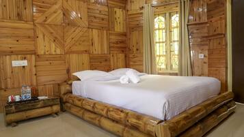 Una habitación con paneles de madera, una cama, una mesita de noche y un ventanal con cortinas.