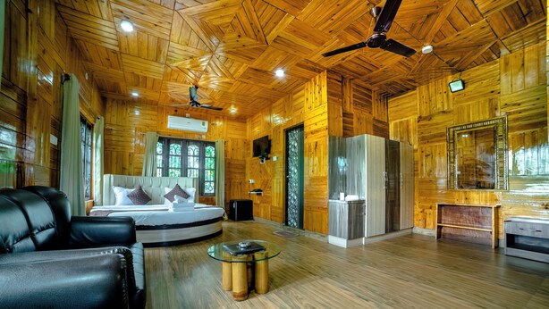 L’intérieur d’un chalet en bois, avec un lit, un canapé en cuir et une table basse en verre.