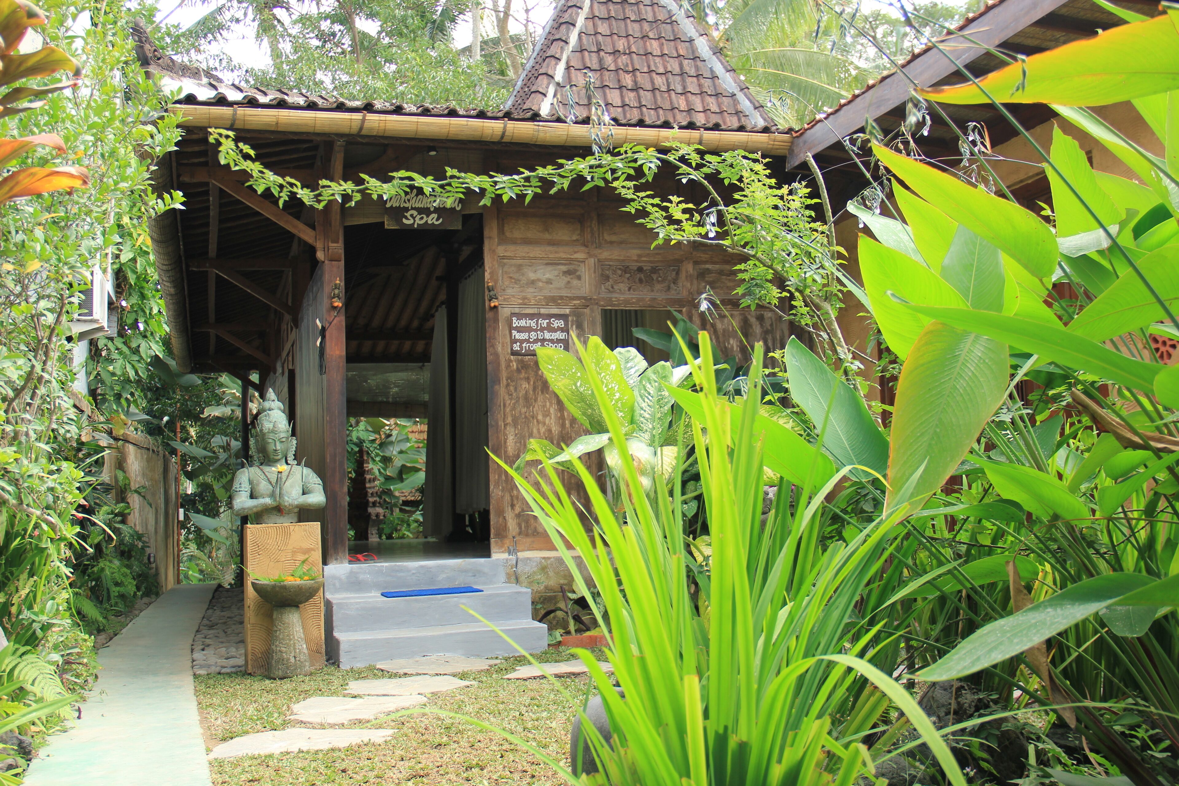 A wooden building with a tiled roof, a statue, and a signboard.