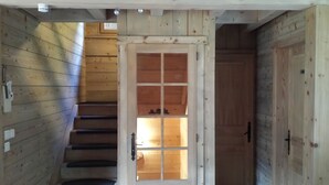 Eine Holztreppe führt zu einem Raum mit einer Tür und einem Fenster.