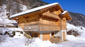 Eine Holzhütte mit Balkon, umgeben von Schnee und Bergen.