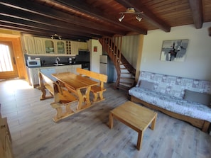 Ein geräumiger Wohnbereich mit einem Holzessttisch, Bänken, einer Couch und einer Treppe, die in einen oberen Bereich führt.